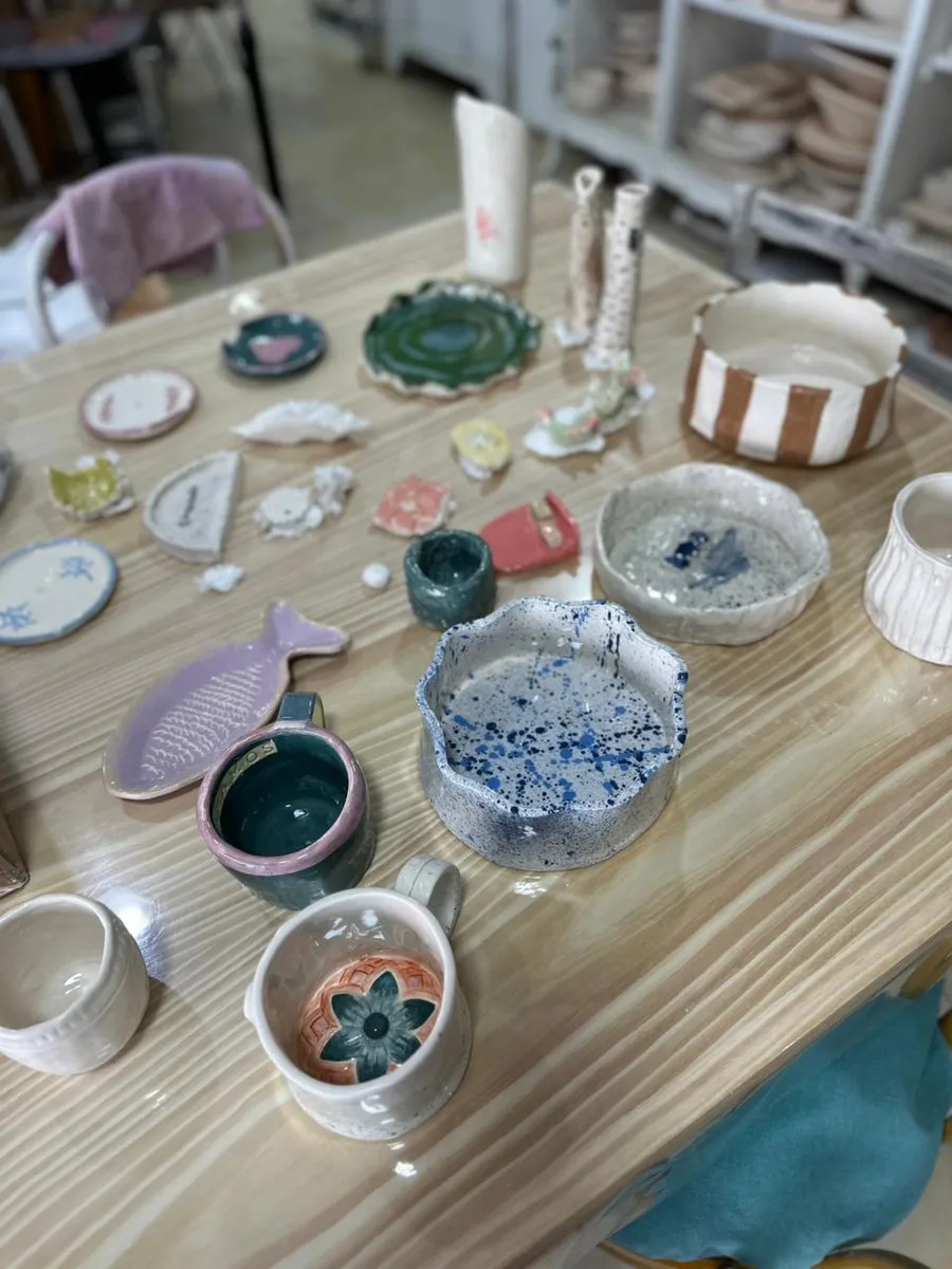 Mesa del taller con piezas de cerámica esmaltadas de distintos colores
