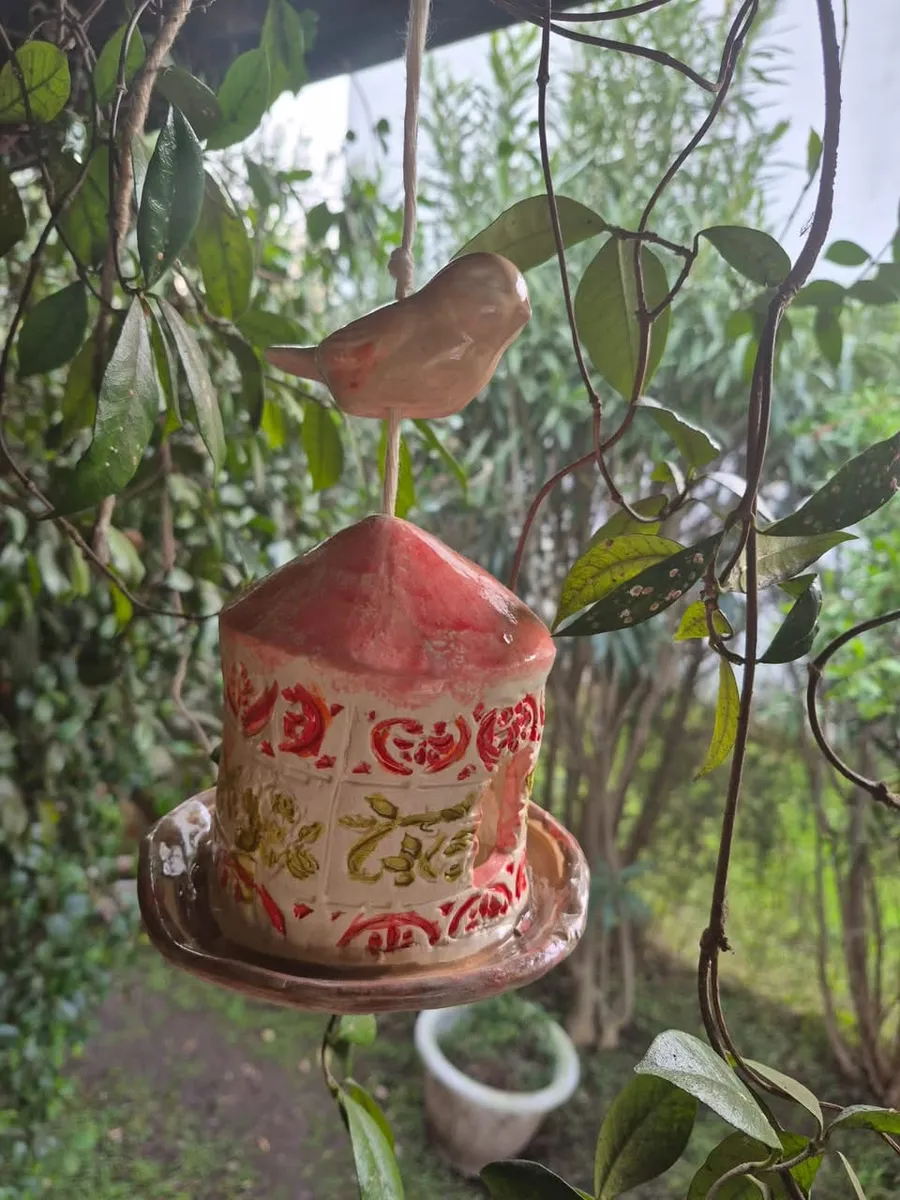 Comedero de pájaros de cerámica colgado entre las ramas