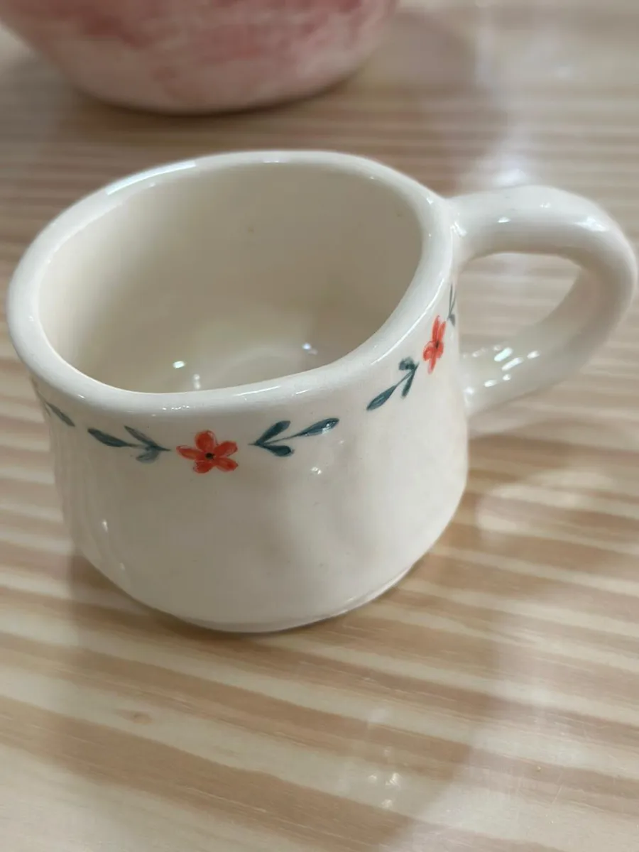 Taza de cerámica blanca con una guirnalda de flores pintada