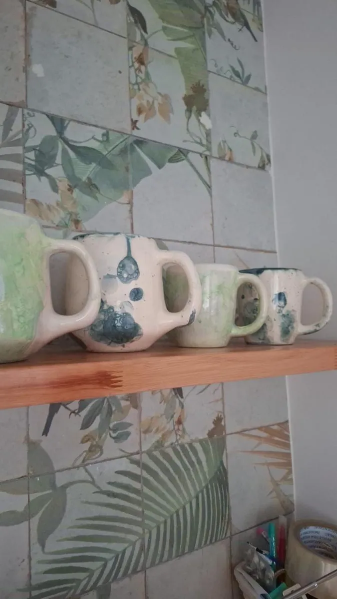 Tazas de cerámica todavía sin esmaltar, en un estante del taller