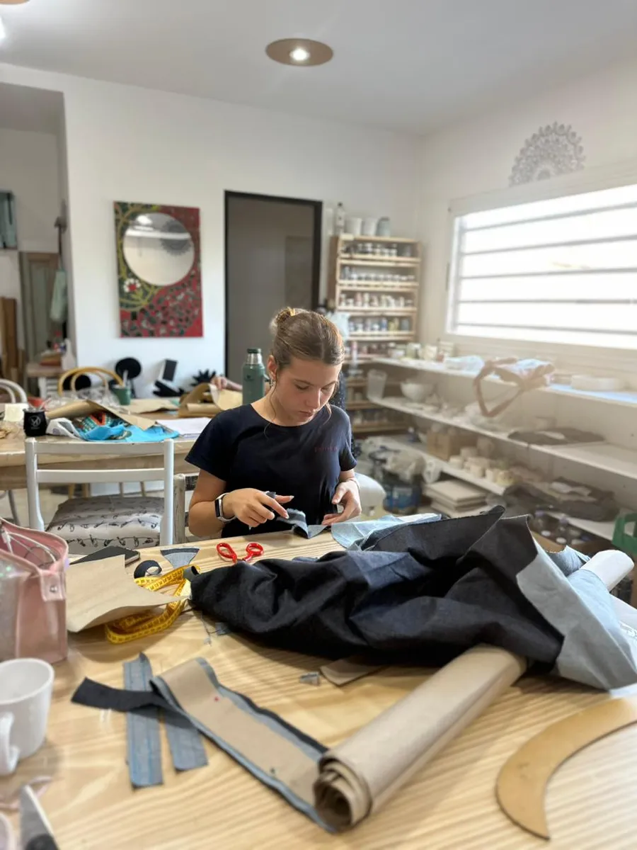 Corte de una tela azul sobre la mesa grande del taller