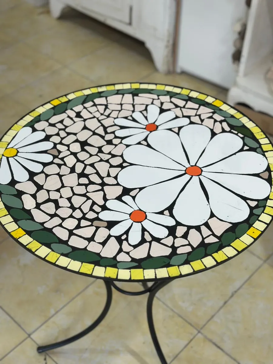 Mesa redonda con mosaico de margaritas blancas sobre fondo de piedra clara