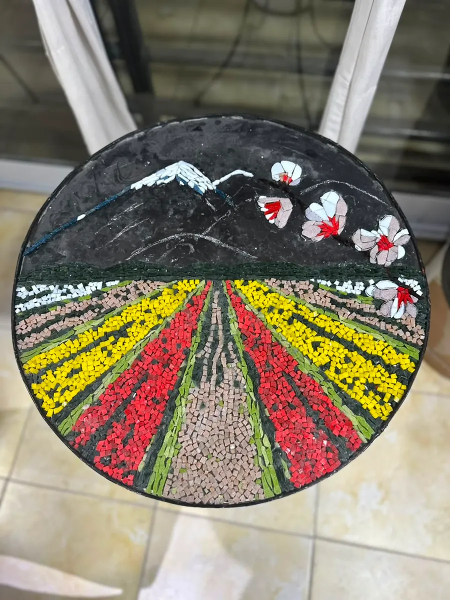 Mesa redonda con un mosaico de campos de tulipanes y montañas nevadas