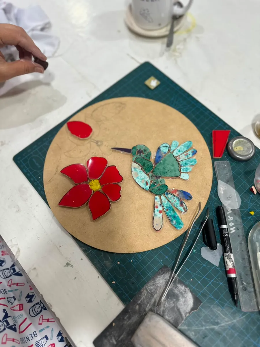 Colibrí y flor de mosaico en pleno armado sobre una base redonda de madera